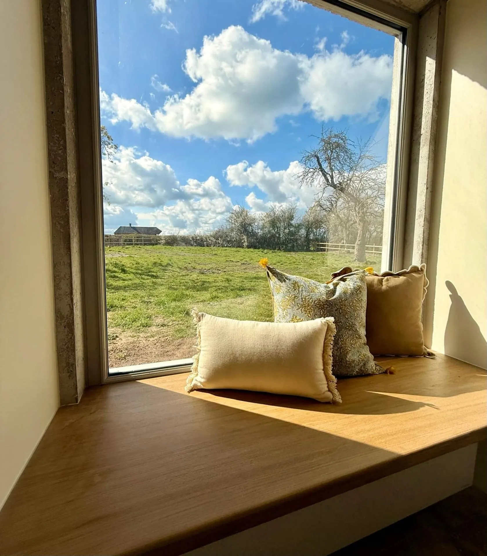 La baie vitrée terminée et sa banquette en bois, avec vue sur la campagne