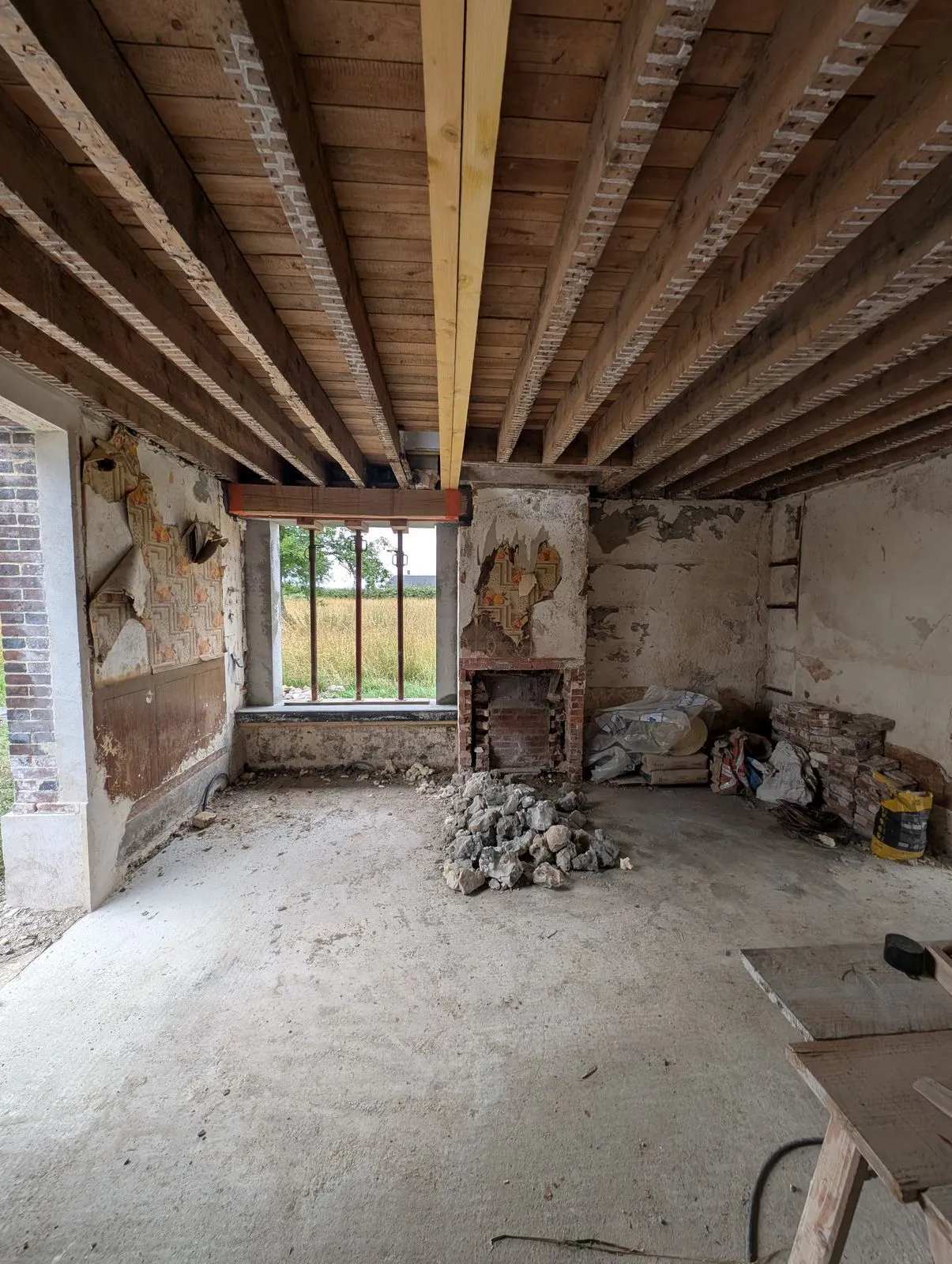 La salle à manger pendant le chantier : la baie vitrée ouverte à gauche de la cheminée, sol mis à nu