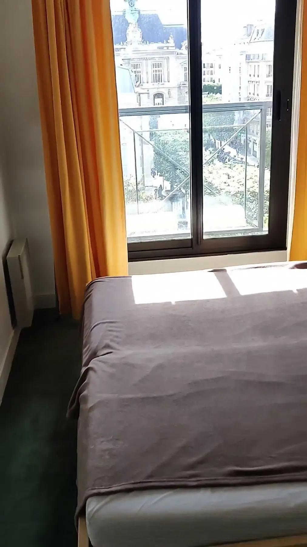 La chambre avant travaux : moquette verte, rideaux orange, lit devant la fenêtre