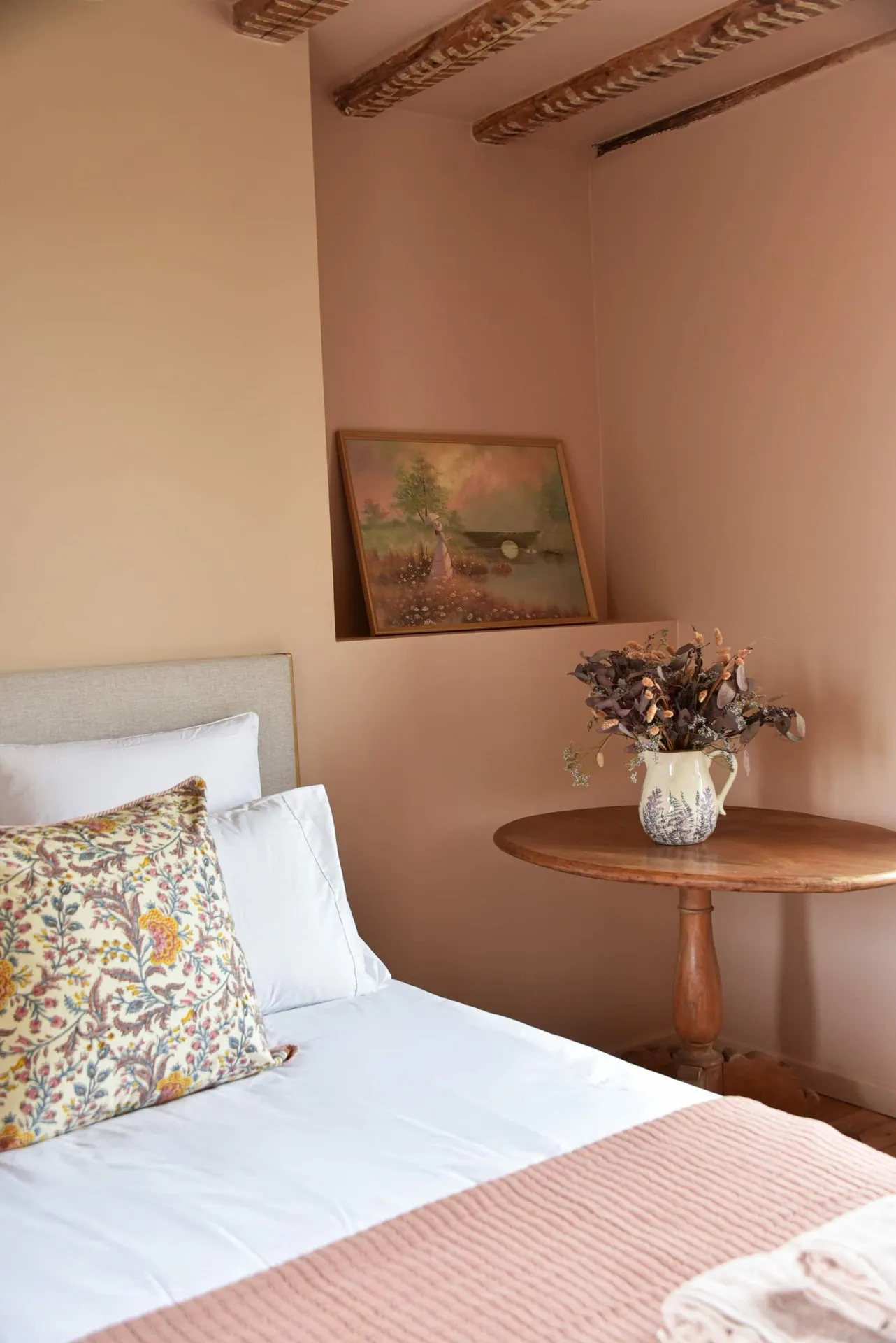 La chambre rose terminée : murs rose poudré, niche avec un tableau, guéridon en bois