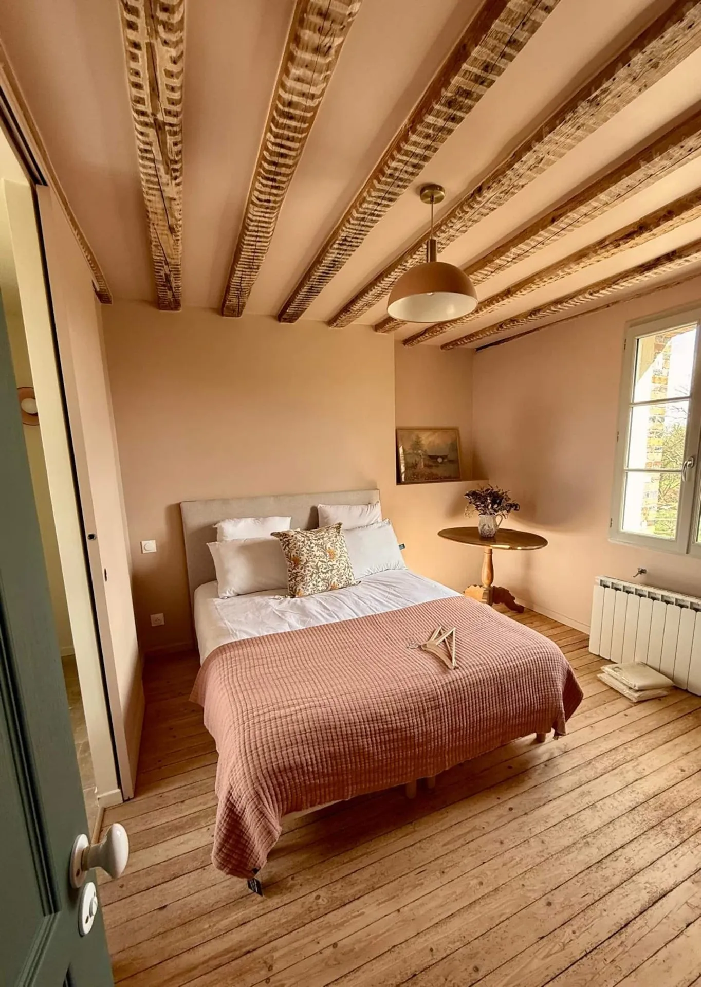 La chambre rose terminée, vue depuis la porte : lit, plancher ancien et solives apparentes