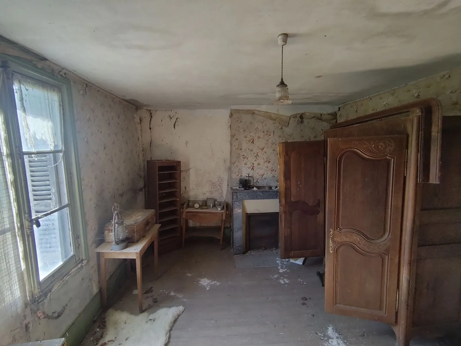 La chambre avant travaux : papier peint défraîchi, armoire ancienne, plancher brut