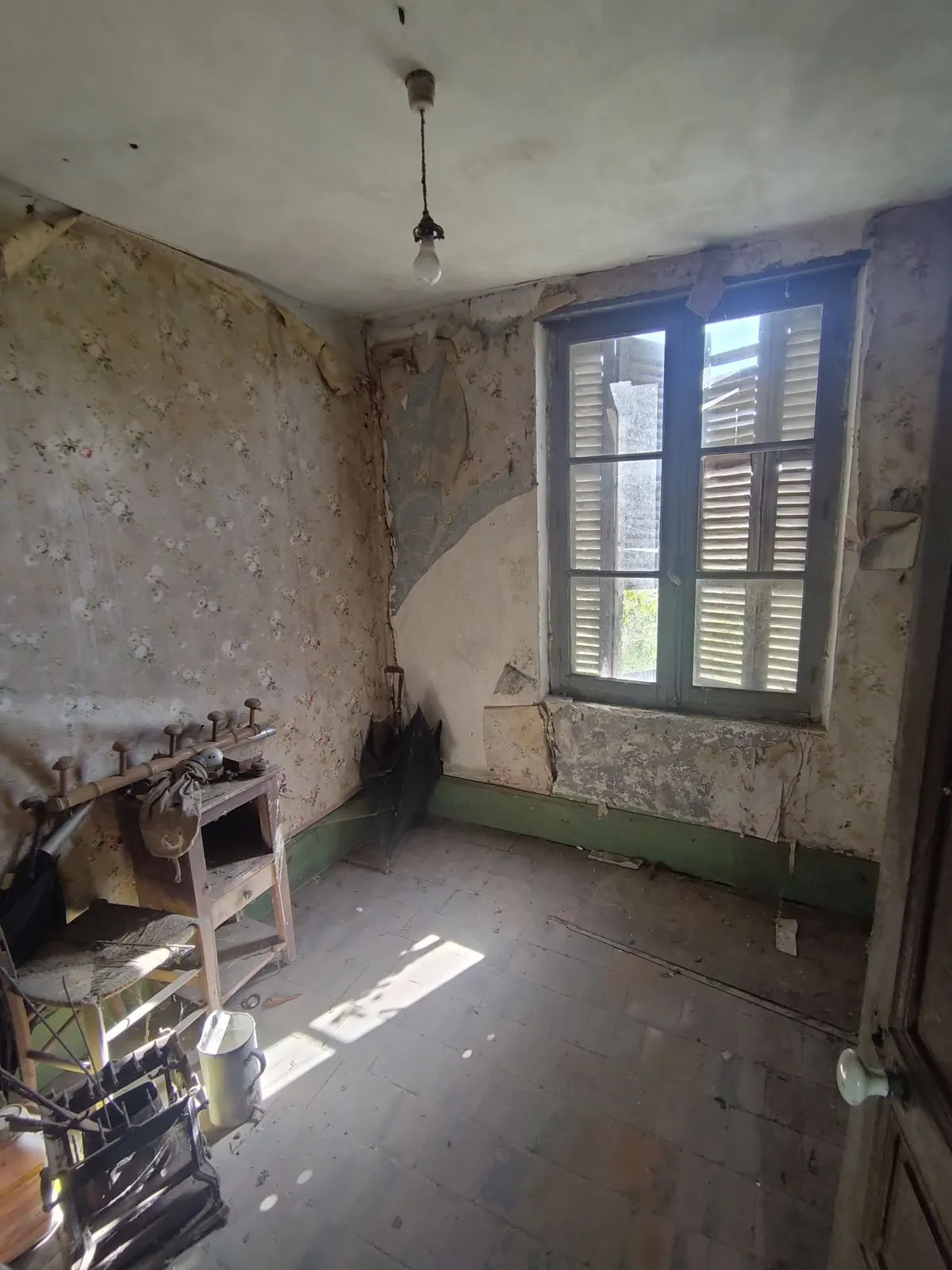 La chambre avant travaux, côté fenêtre : persiennes fermées, murs écaillés