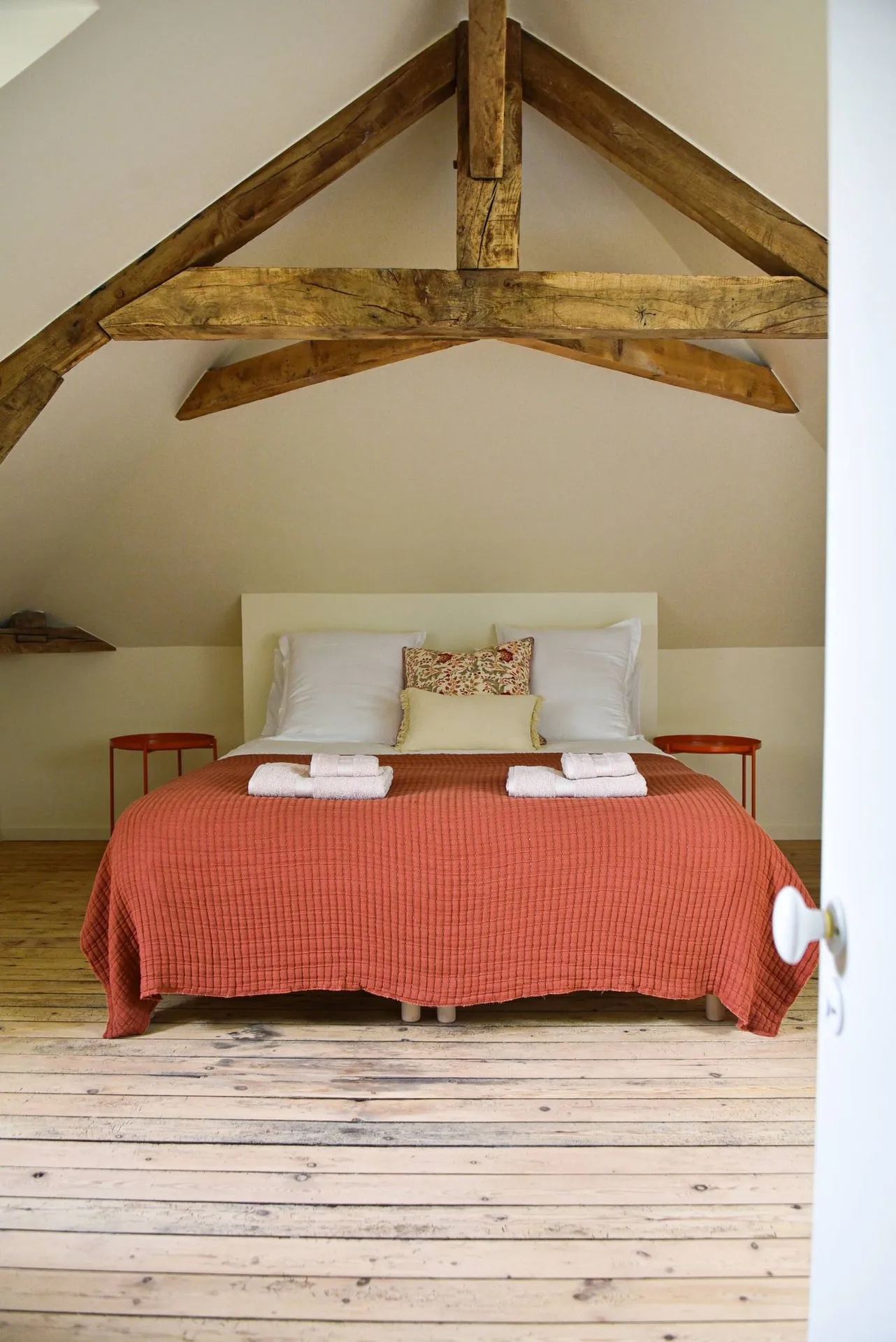 La chambre sous les combles terminée : lit sous la charpente apparente, plancher ancien