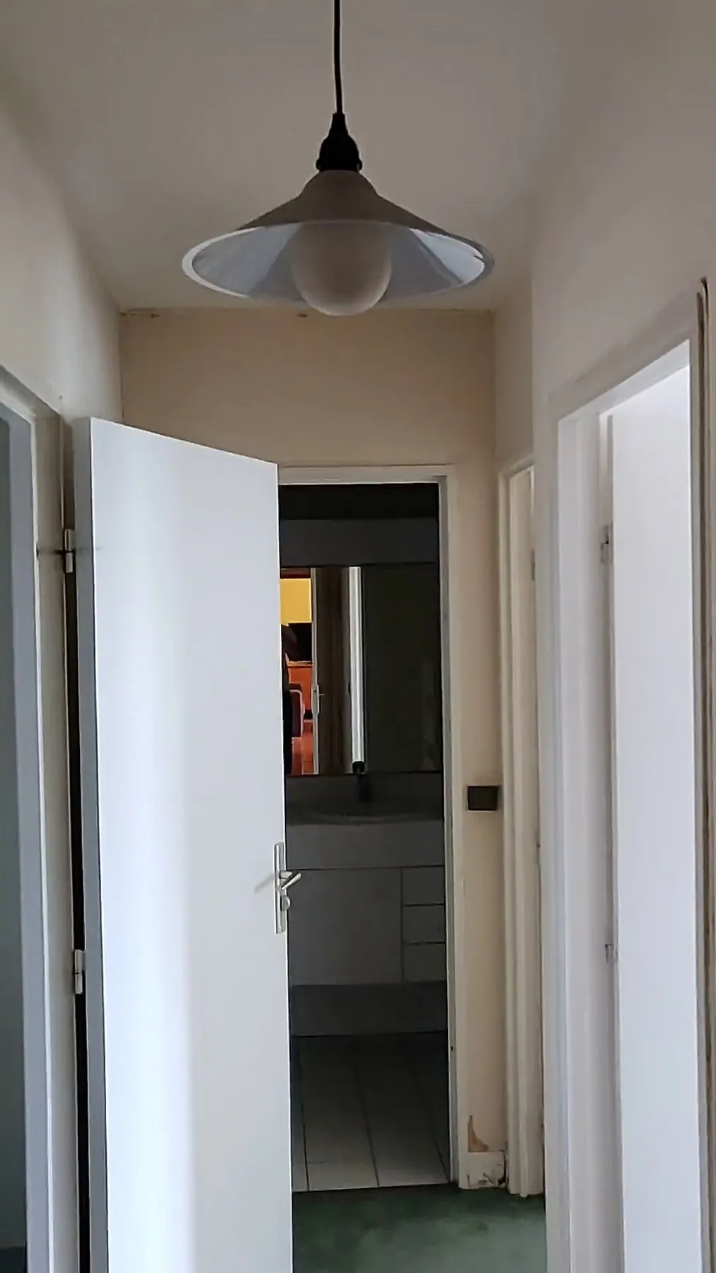 Le couloir avant travaux : moquette verte, portes blanches en enfilade, suspension au plafond