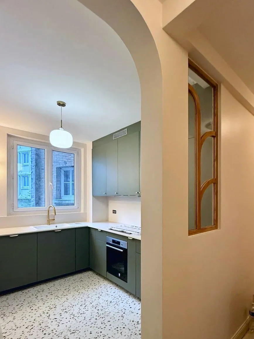 La cuisine vue du couloir à travers la nouvelle arche, avec la verrière en bois à droite