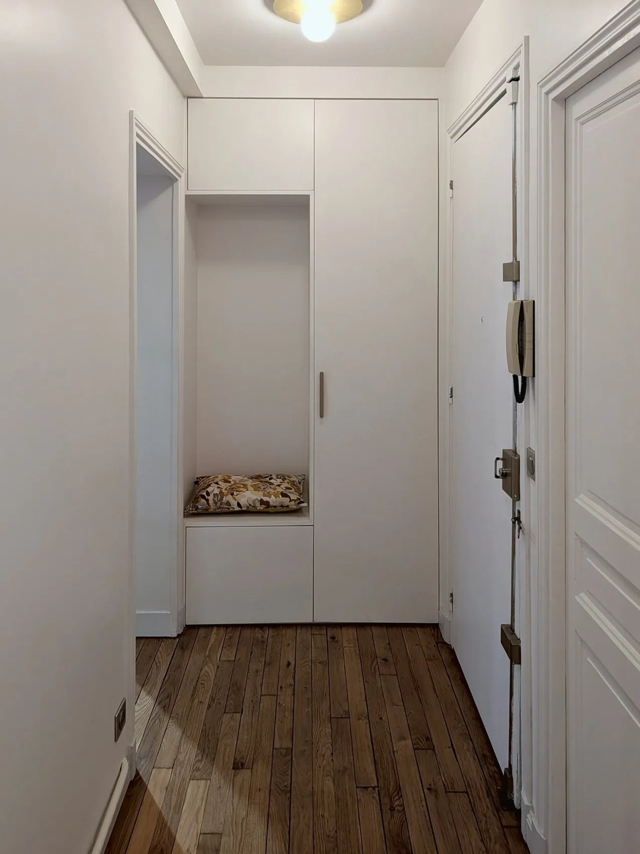 L'entrée terminée : menuiserie sur mesure toute hauteur avec banquette en niche, parquet rénové