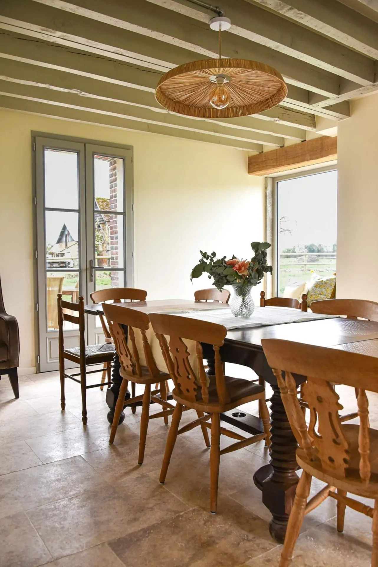 La salle à manger terminée : grande table en bois, porte-fenêtre et baie vitrée sur le jardin