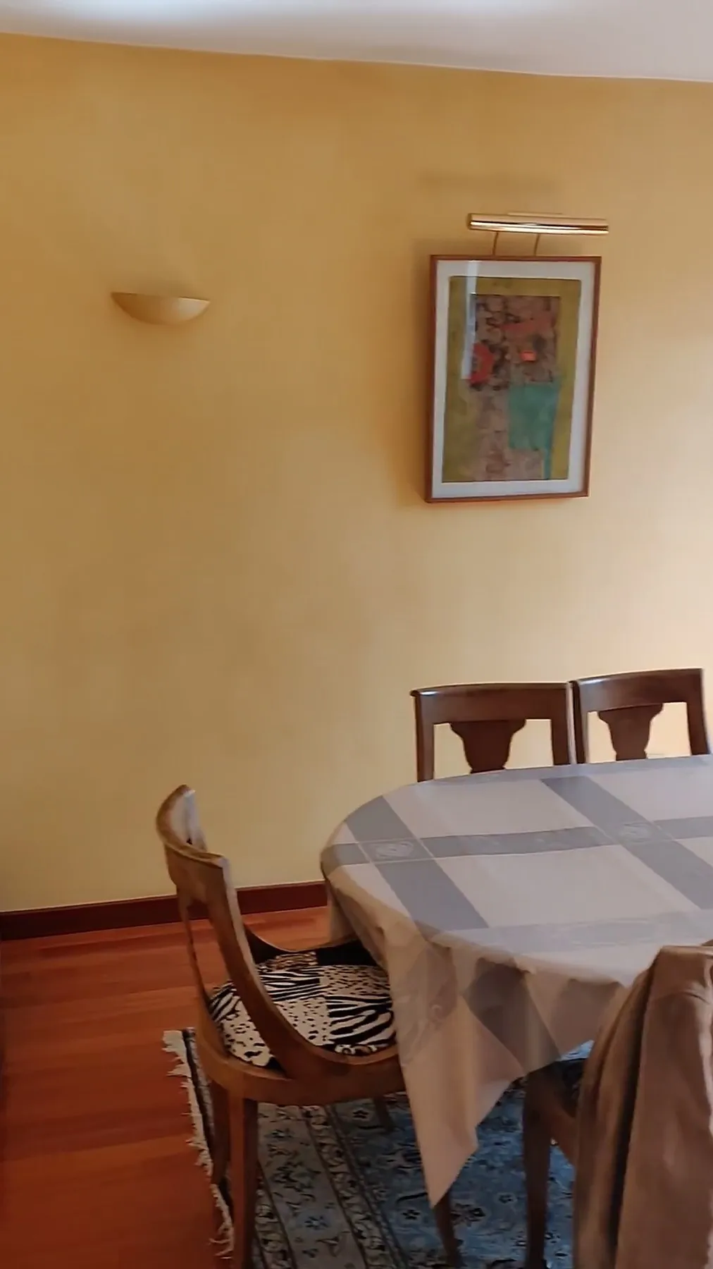 La salle à manger avant travaux : murs jaunes, table ovale et chaises en bois