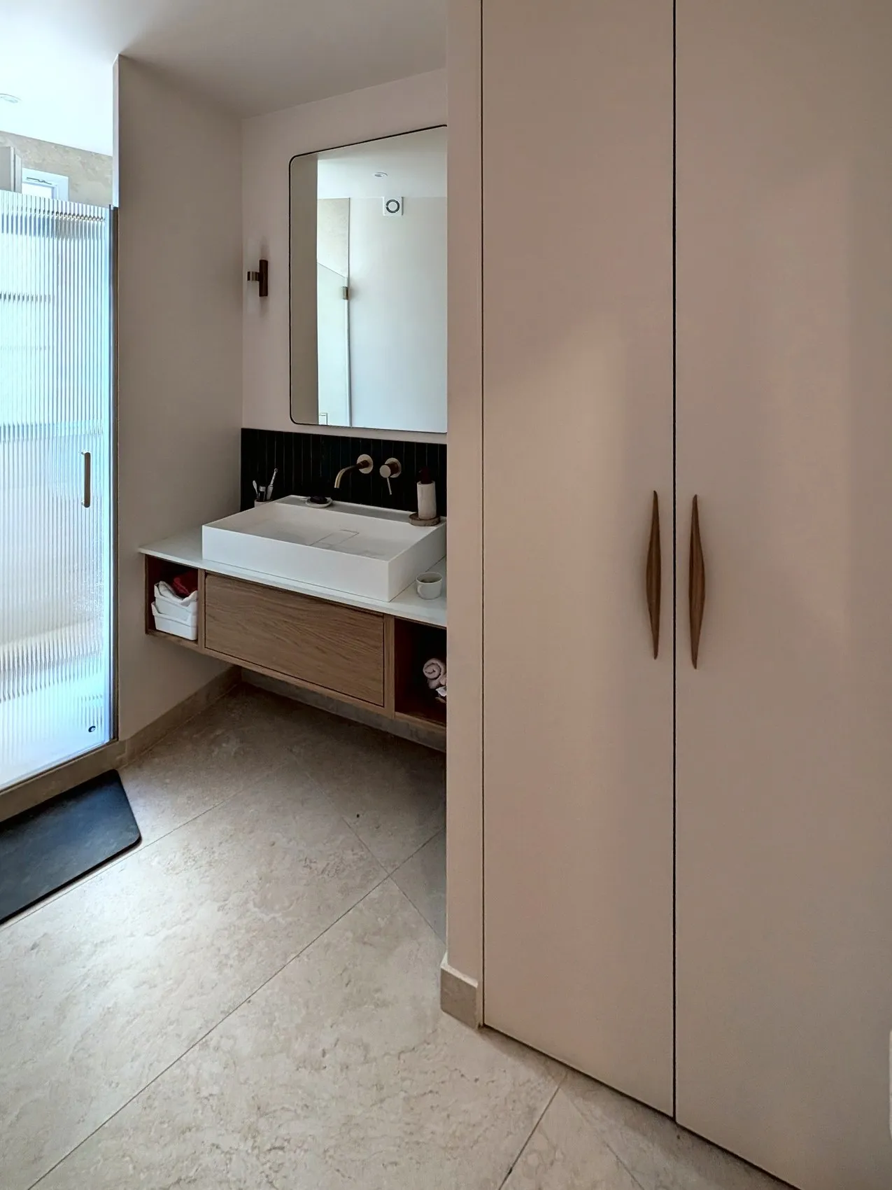 La salle de bain terminée : vasque suspendue, grand placard sur mesure et douche à l'italienne