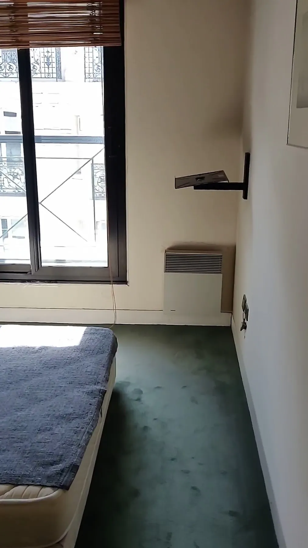 La seconde chambre avant travaux : moquette verte, lit sous la fenêtre au store en bois