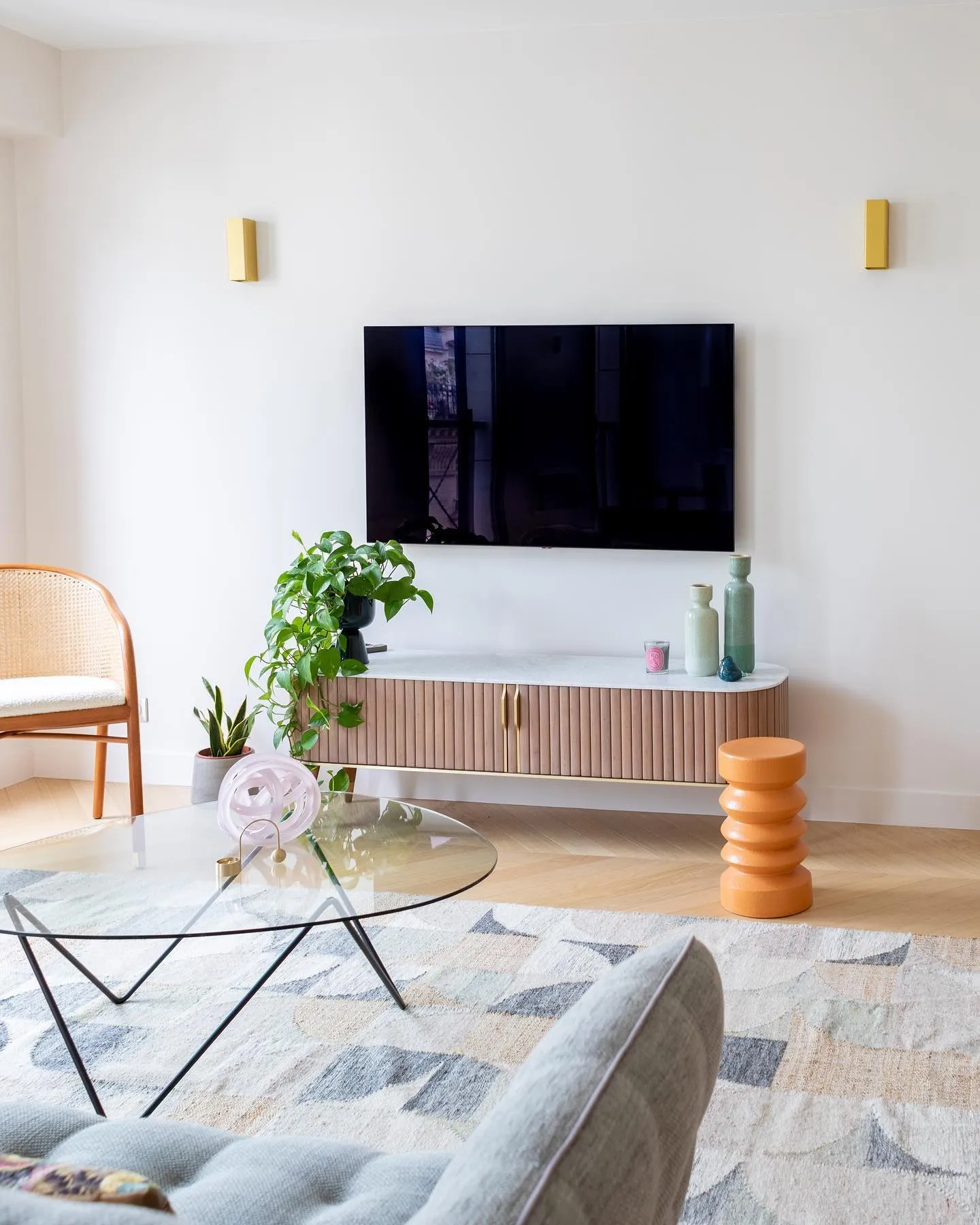 Le séjour terminé : murs clairs, parquet à chevrons, meuble bas sous la télévision