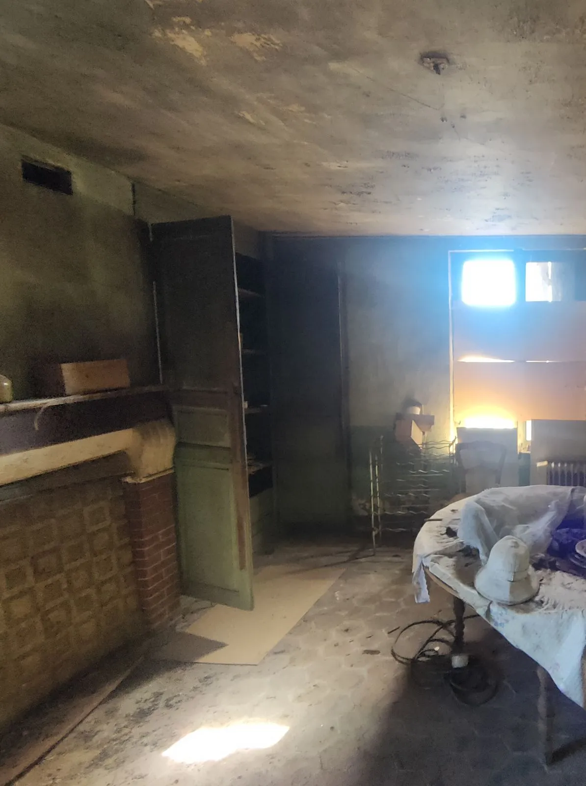 Le séjour avant travaux : pièce sombre, murs et plafond noircis, cheminée en brique à gauche