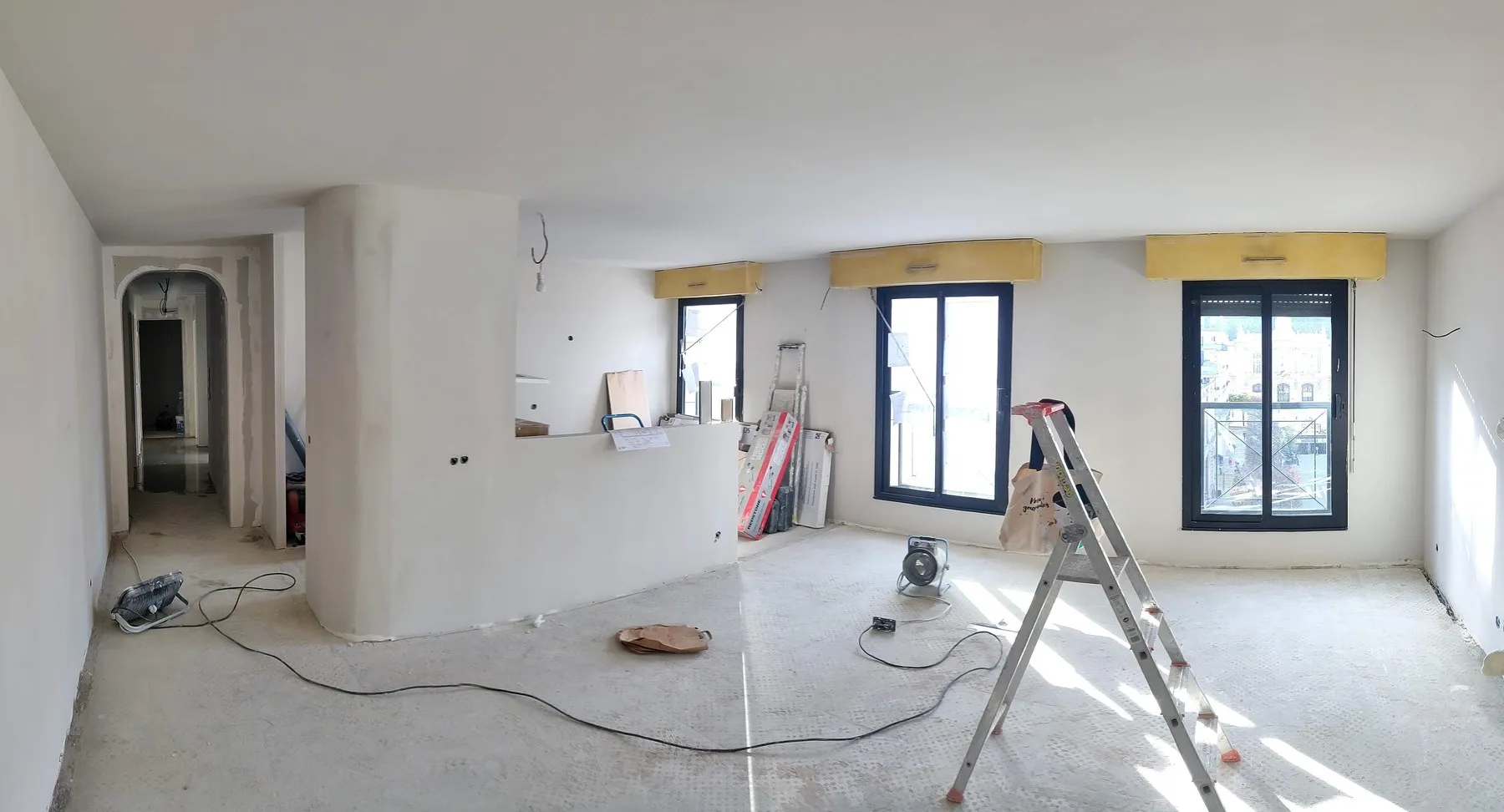 Le séjour pendant le chantier : cloisons posées, sol ragréé, murs en attente de peinture