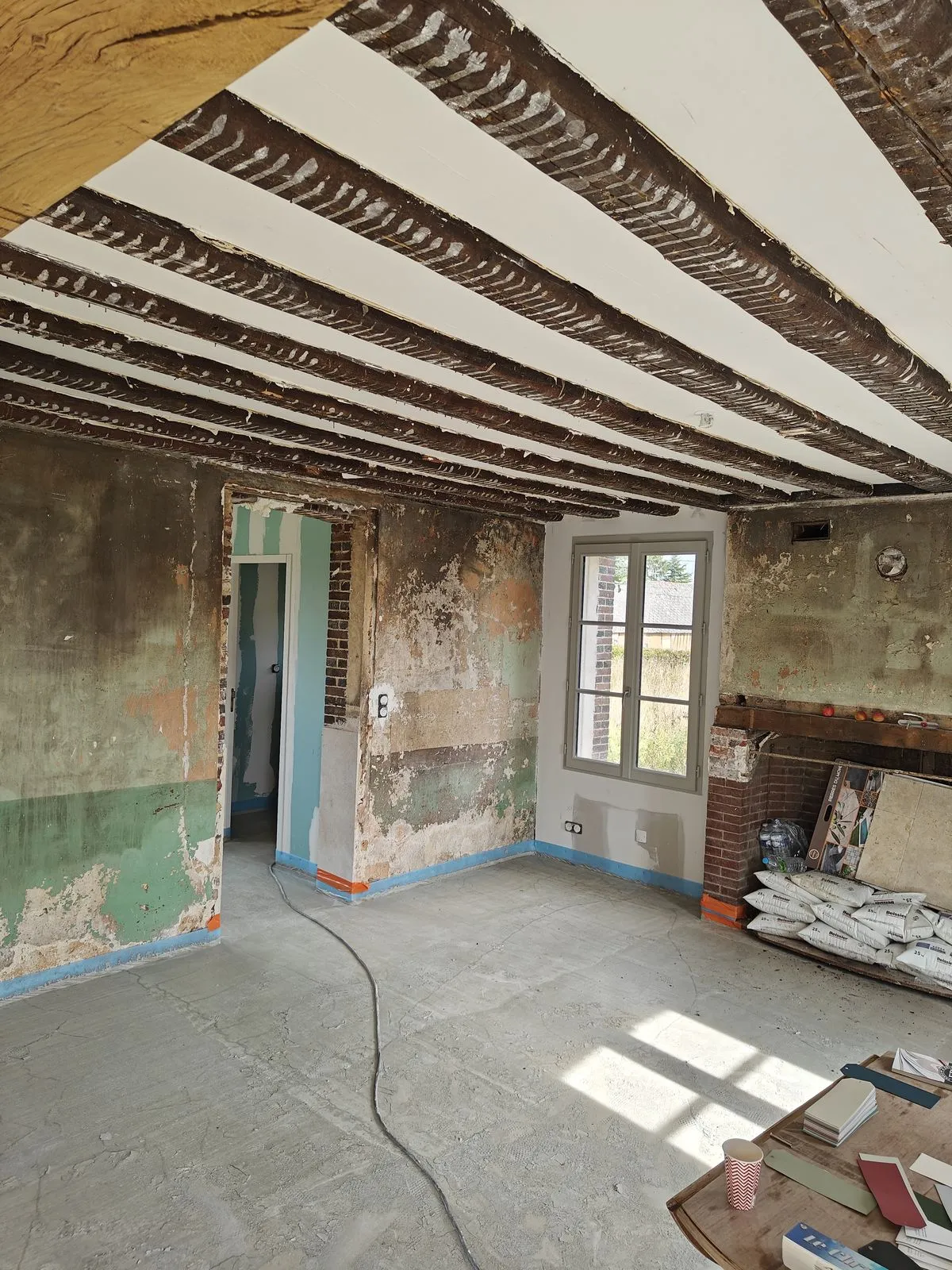 Le séjour pendant le chantier : solives apparentes, murs mis à nu, cheminée en brique